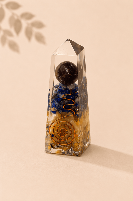 Orgoniet obelisk met lapis lazuli en gele aventurijn op een beige gebladerde achtergrond