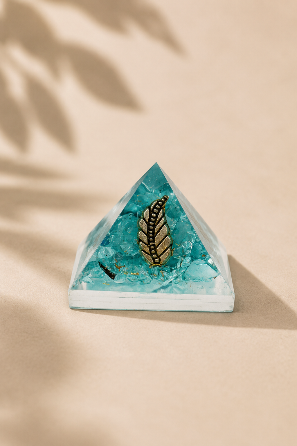 Orgoniet piramide 25 mm met edelsteenchips en koper op een beige gebladerde achtergrond