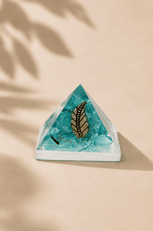 Orgoniet piramide 25 mm met edelsteenchips en koper op een beige gebladerde achtergrond