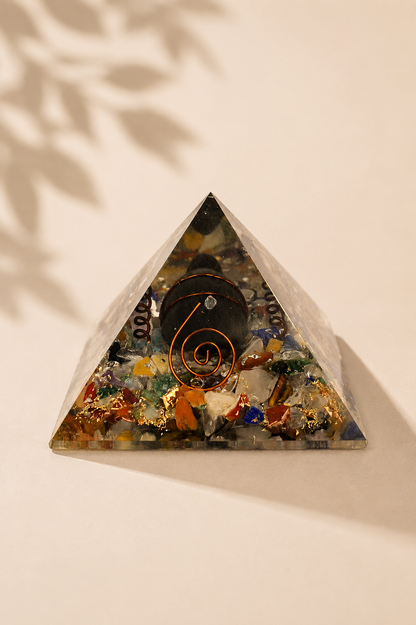 Orgoniet piramide 60 mm met edelsteenchips, koper en schildpad op een gebladerde beige achtergrond