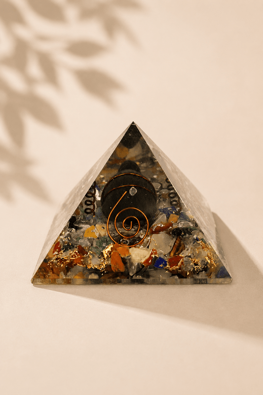 Orgoniet piramide 60 mm met edelsteenchips, koper en schildpad op een gebladerde beige achtergrond