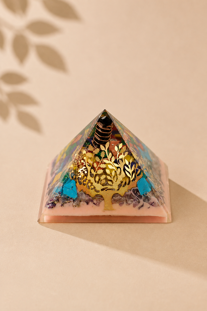Orgoniet piramide 70 mm met levensboom en edelsteenchips op een beige gebladerde achtergrond