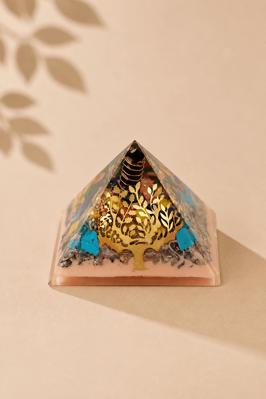 Orgoniet piramide 70 mm met levensboom en edelsteenchips op een beige gebladerde achtergrond