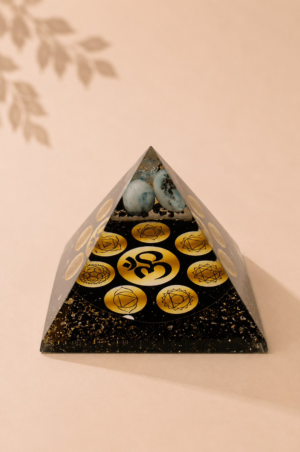 Orgoniet piramide Midnight OM Chakra op een beige gebladerde achtergrond