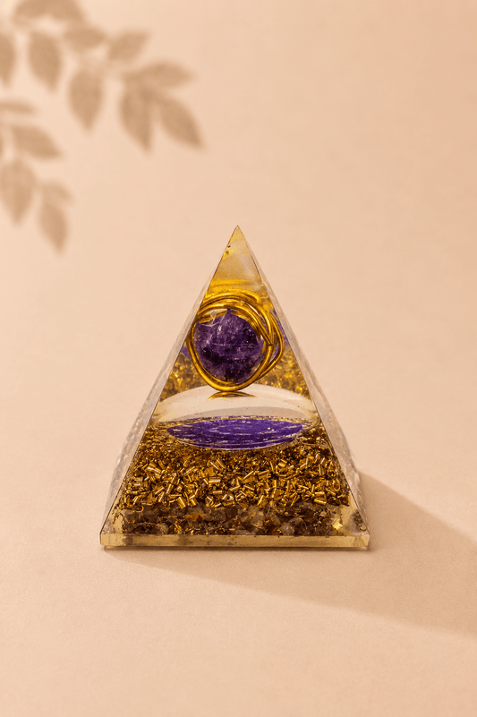 Orgoniet piramide met amethist en koperspiraal op een beige gebladerde achtergrond