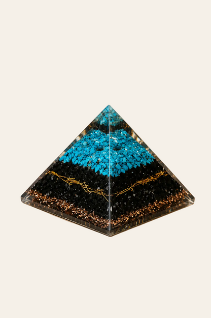 Orgoniet piramide met turquoise en zwarte toermalijn op een lichte beige achtergrond als een productfoto