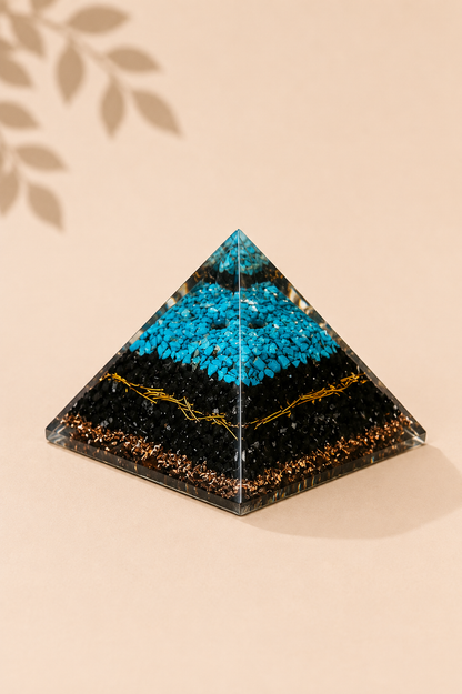 Orgoniet piramide met turquoise en zwarte toermalijn op een gebladerde beige achtergrond