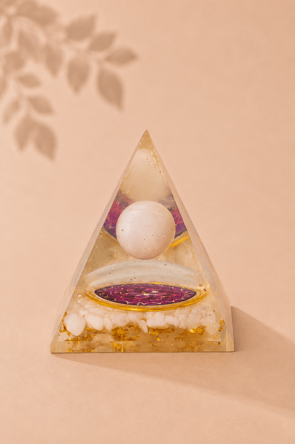 Orgoniet piramide met zwevende bergkristal bol met beige gebladerde achtergrond