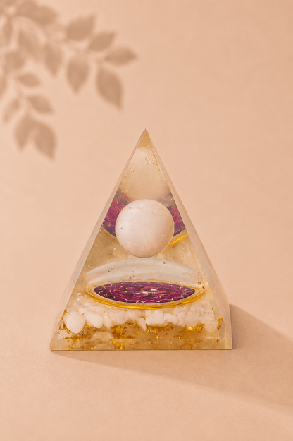 Orgoniet piramide met zwevende bergkristal bol met beige gebladerde achtergrond