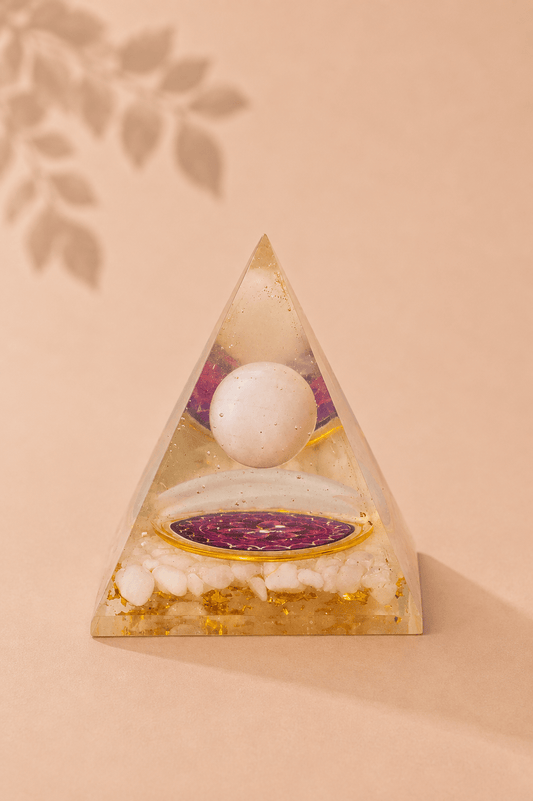 Orgoniet piramide met zwevende bergkristal bol met beige gebladerde achtergrond