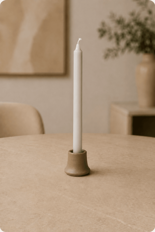 Puur natuurwas dinerkaarsen zilvergrijs op lichtbeige tafel in een woonkamer met dieptezicht
