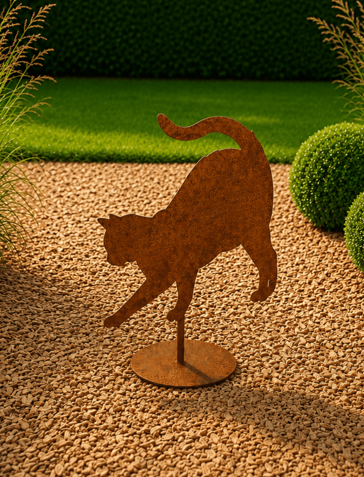 Roestige decoratieve kat op vloerplaat spelend in e tuin tussen de planten en bloemen
