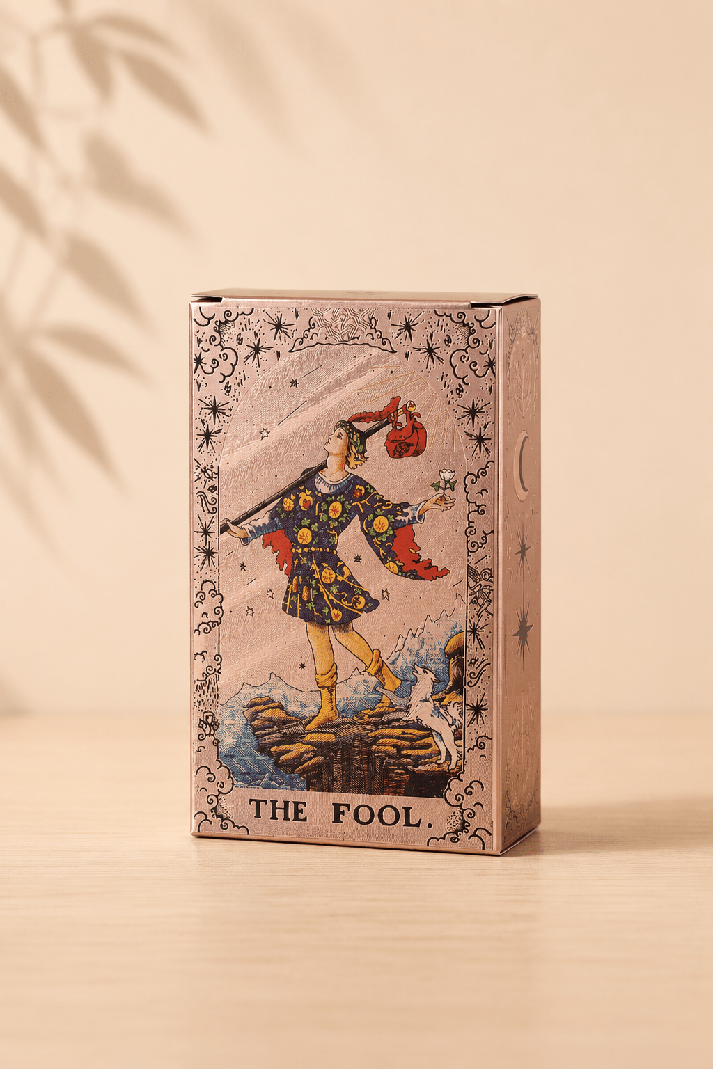 Roségouden tarotkaartenset met maanfasen en boekje op een beige gebladerde achtergrond