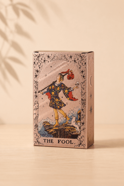 Roségouden tarotkaartenset met maanfasen en boekje op een beige gebladerde achtergrond