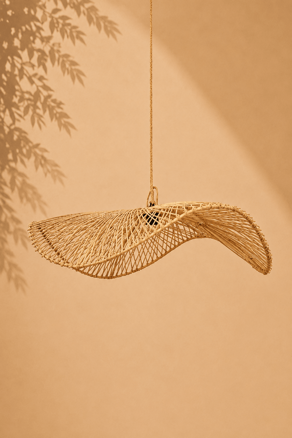 Rotan hanglamp in organische golfvorm op een beige gebladerde achtergrond