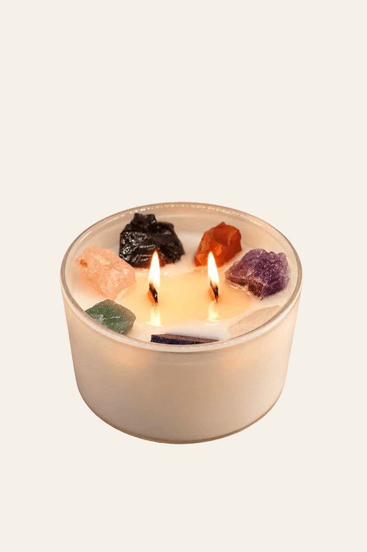 Seven Chakra kristalkaars van sojawas met zeven edelstenen en twee brandende houten lonten op warme beige achtergrond