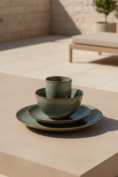Tabo design serviesset in groen keramiek uit 4 delen op een ichtbeige afel in de tuin met geblurd dieptezicht