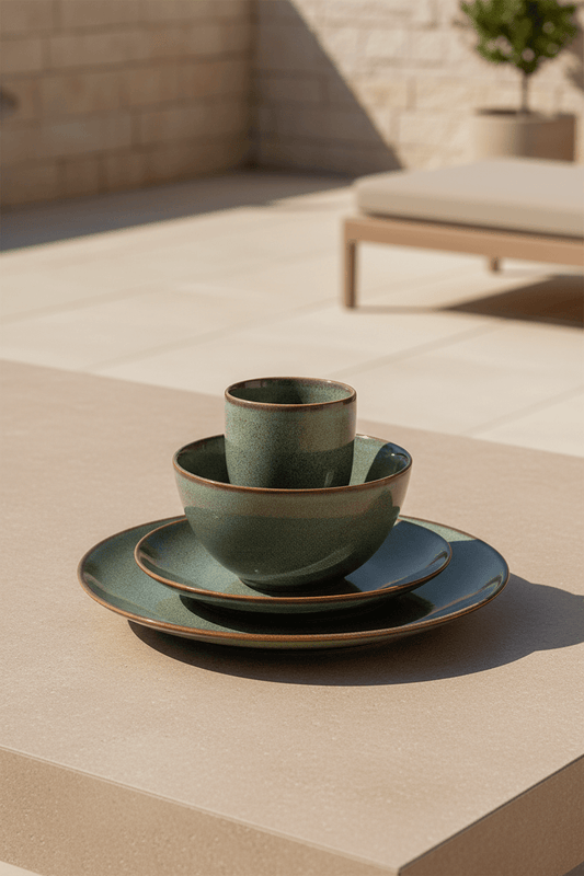 Tabo design serviesset in groen keramiek uit 4 delen op een ichtbeige afel in de tuin met geblurd dieptezicht