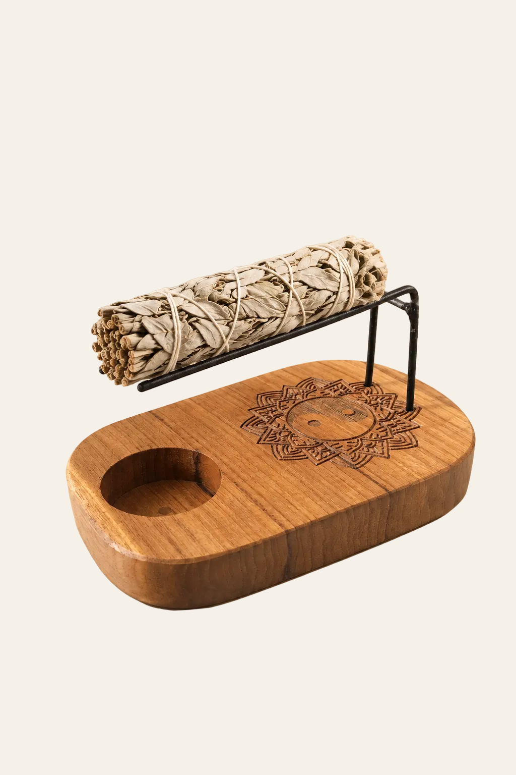 Teakhouten smudgehouder met yin-yang motief en smudgebundel op zwarte metalen steun op beige producttemplate