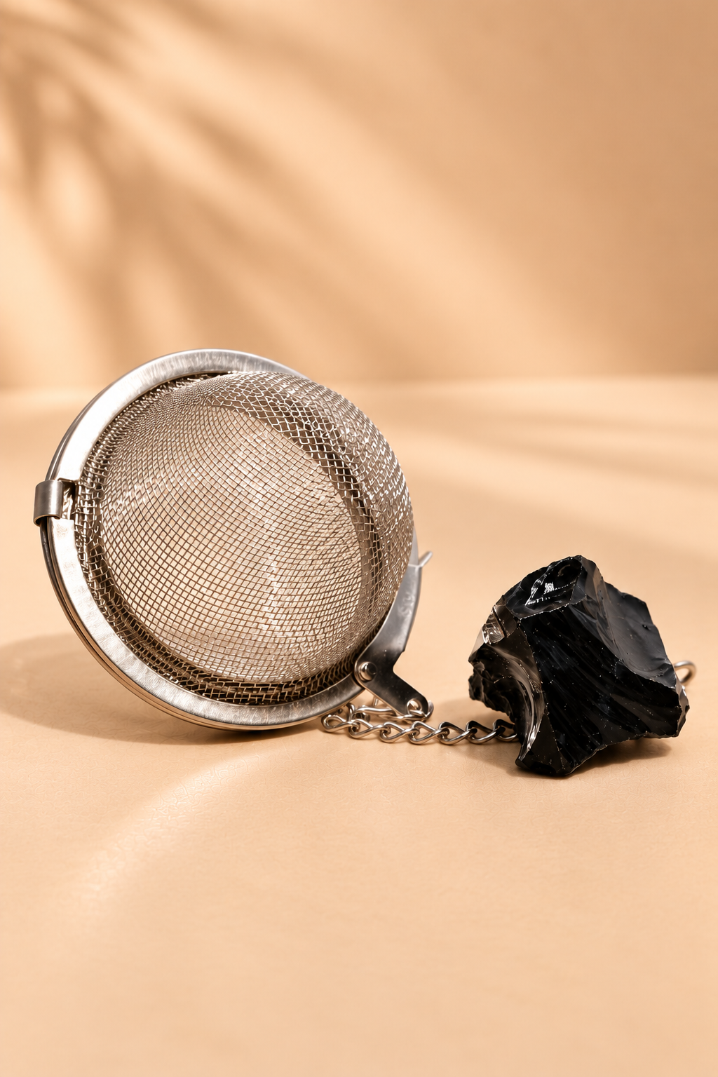 Theezeef met zwarte obsidiaan edelsteen en zwarte geschenkdoos op warme beige productachtergrond