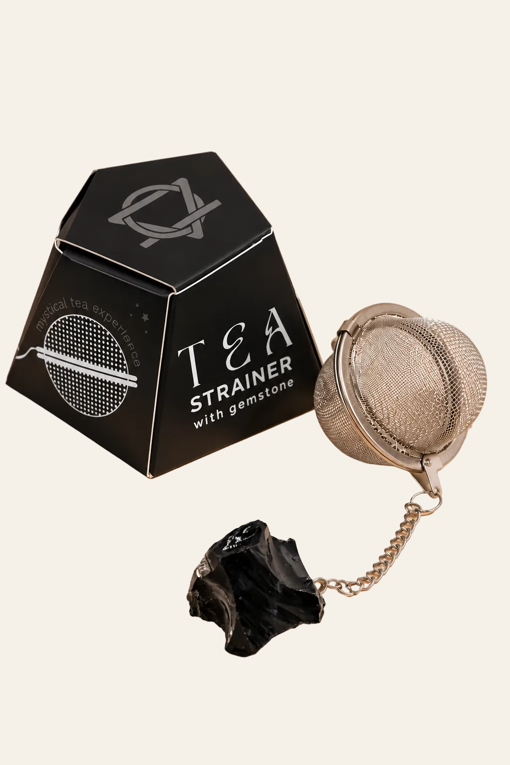 Fijnmazige metalen theezeef met kettinkje en ruwe zwarte obsidiaan edelsteen op lichtbeige achtergrond