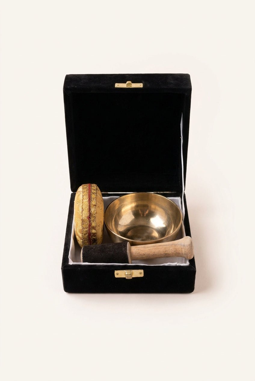 Goudkleurige messing klankschaal 9 cm met zwart decoratief kussen en houten klopper op witte achtergrond