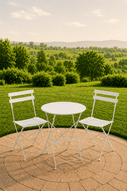 Witte metalen tuinbistroset met ronde tafel en twee stoelen op een betegeld terras met dieptezicht over een groen landschap
