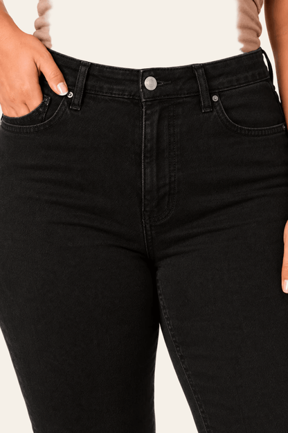 Detail van taille, sluiting en voorzakken van zwarte skinny damesjeans.