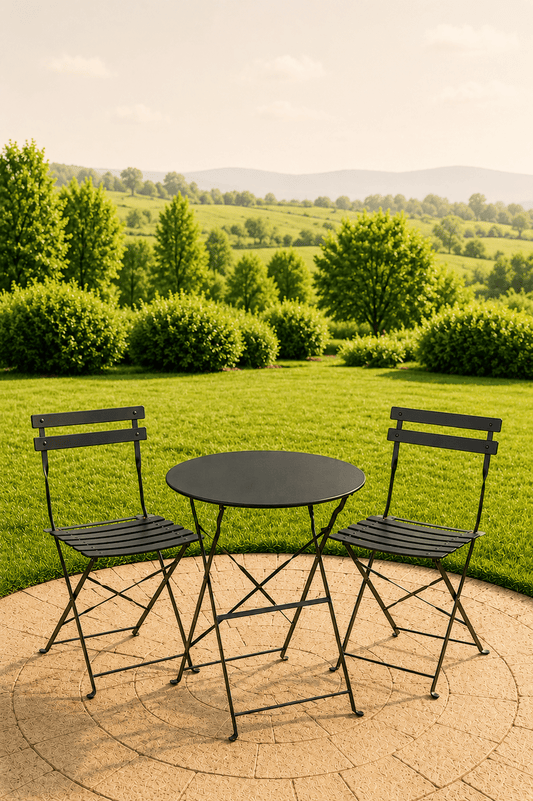 Zwarte metalen tuinbistroset met ronde tafel en twee stoelen op een betegeld terras met dieptezicht over een groen landschap
