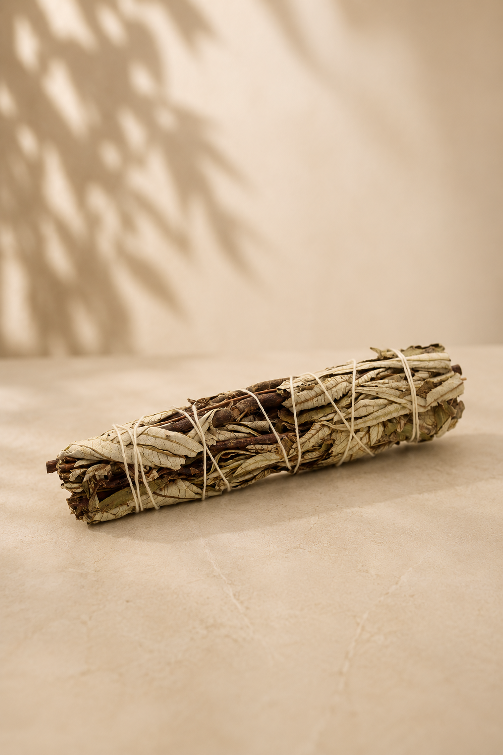 Zwarte salie smudge stick 15 cm liggend op een marmeren beige achtergrond 