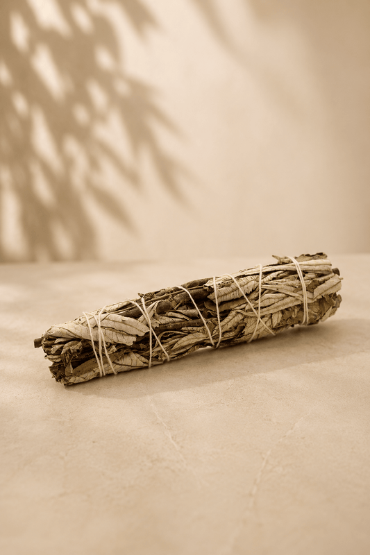 Zwarte salie smudge stick 15 cm liggend op een marmeren beige achtergrond 
