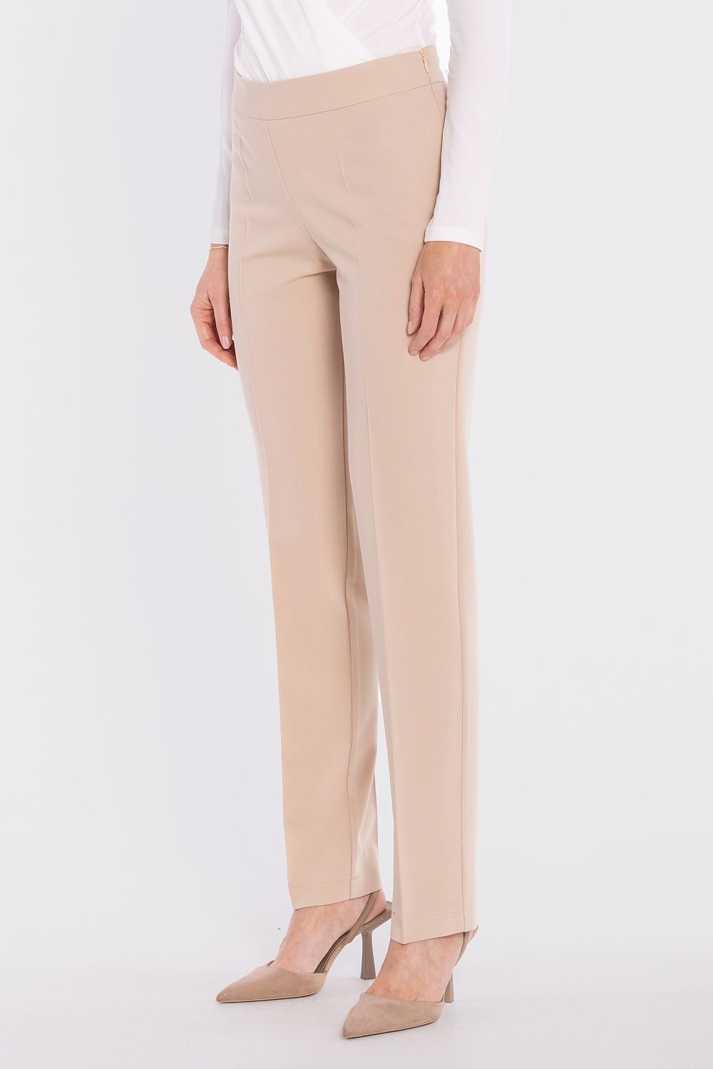 Detail van de beige pantalon brengt de effen tailleband en rechte snit nadrukkelijk in beeld op het model.