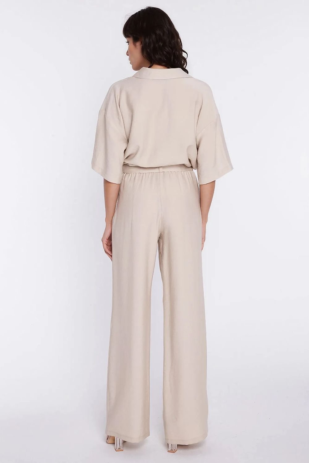 Achterkant van de lichtbeige pantalon brengt de hoge taille en wijde pijpen aan de rugzijde duidelijk in beeld.