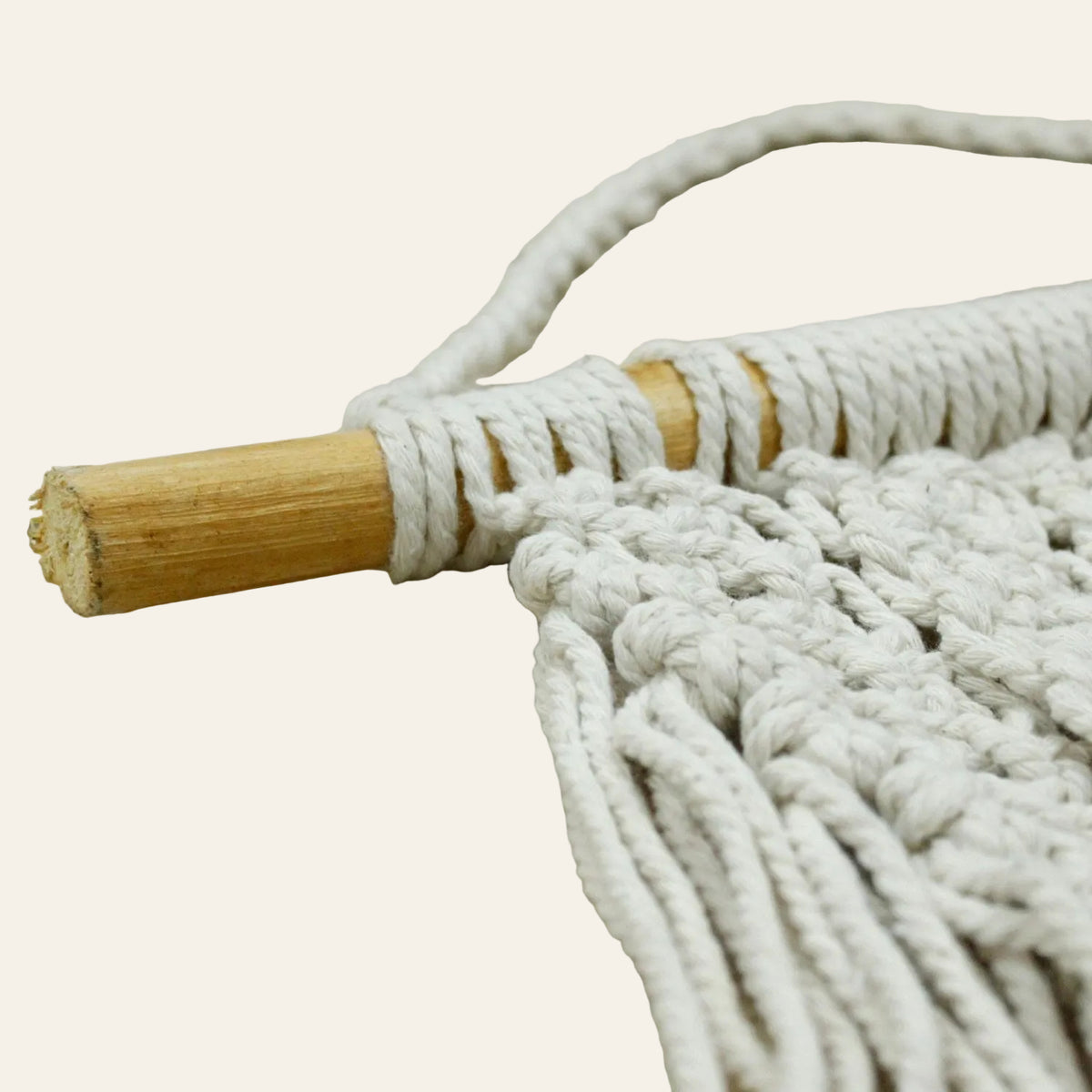 Detailfoto hoe e macrame rond de stok gedraait is en hoe men de witte macrametouwen zijn beginnen knopen